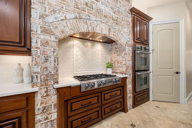 Classic and neutral kitchen is equipped with Jenn-Air appliances, including a gas-burning range. | Image 12