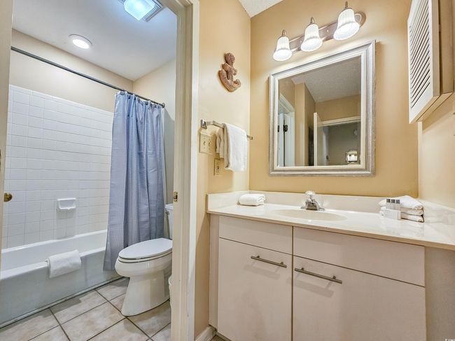 Full bath featuring toilet, tile patterned floors, vanity, and shower / bath combo with shower curtain | Image 33
