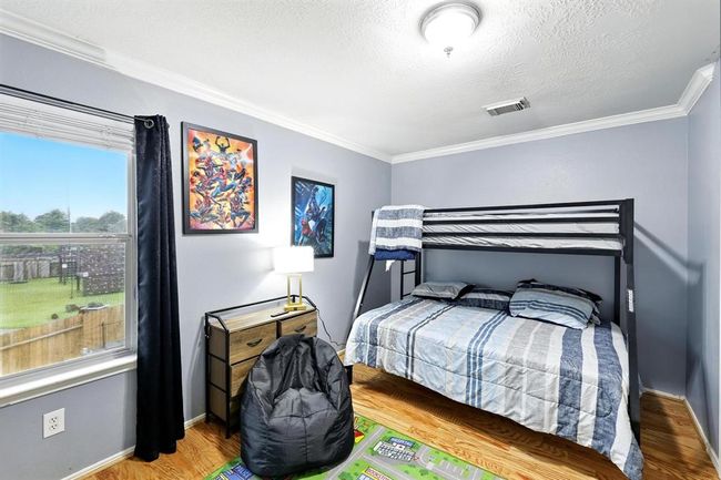 This versatile secondary bedroom features durable wood flooring, a wide window with backyard views, with space for flexible furniture arrangements. | Image 21