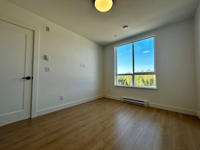 Unfurnished room featuring wood finished floors, baseboard heating, and baseboards | Image 13
