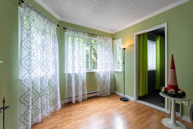 Spare room featuring a textured ceiling, light wood-type flooring, crown molding, and baseboards | Image 6