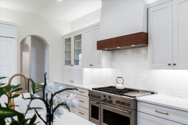 Kitchen featuring double oven range, premium range hood, tasteful backsplash, and light countertops | Image 11