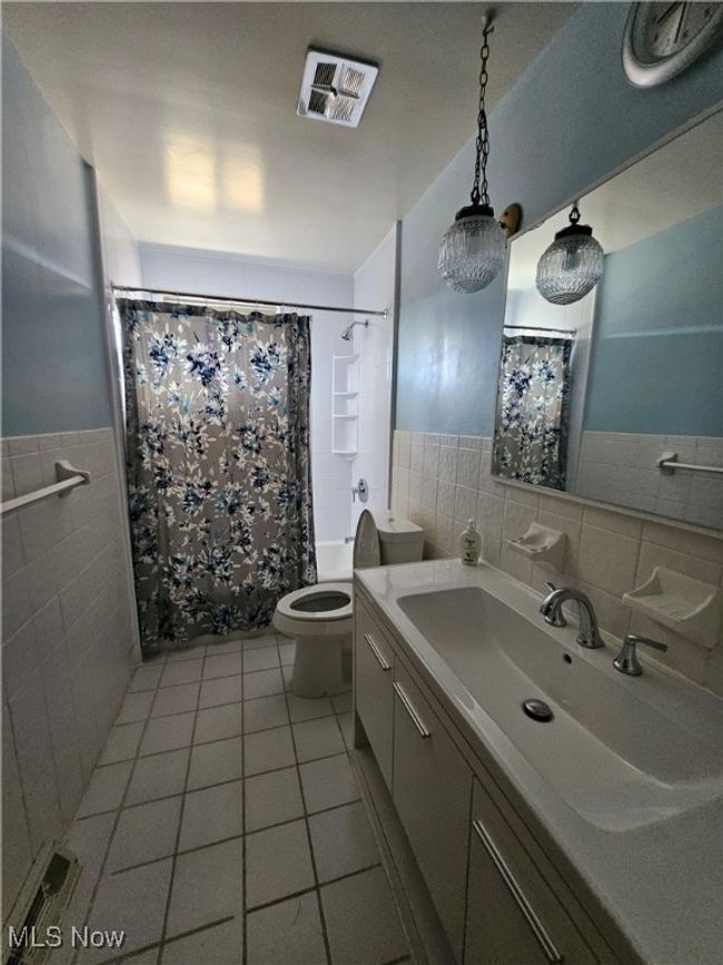 Full bath featuring tile walls, tile patterned floors, visible vents, and toilet | Image 8