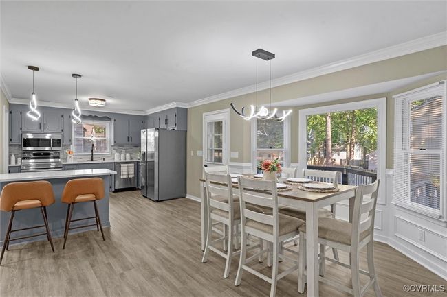 Dining area featuring ornamental molding, a chandelier, and light wood-style floors | Image 19