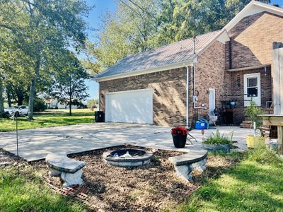 Large concrete parking area with firepit and patio area. | Image 3