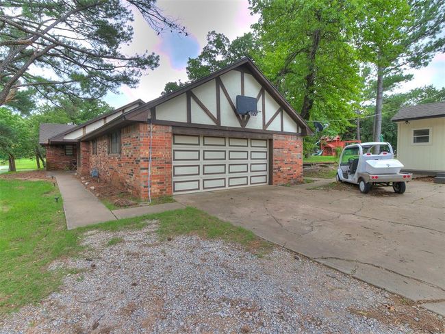 View of side of property with brick siding, concrete driveway, and a garage | Image 6