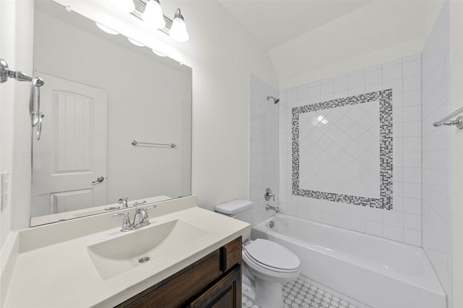 Full bathroom featuring vanity, washtub / shower combination, tile patterned floors, and toilet | Image 33