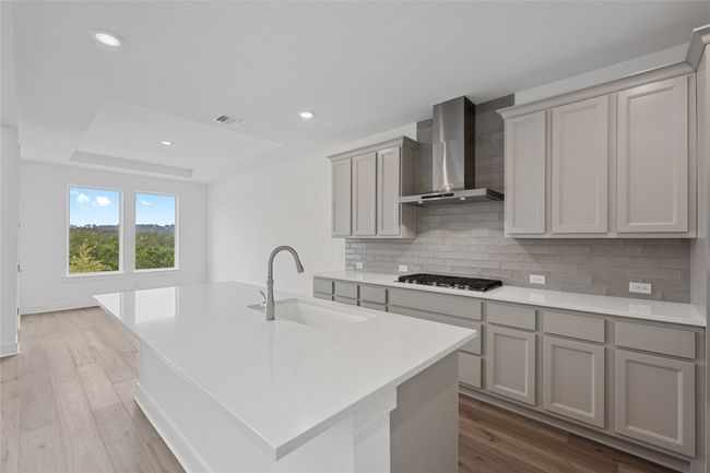 Kitchen with a sink, wall chimney range hood, stainless steel gas cooktop, backsplash, and gray cabinets | Image 7
