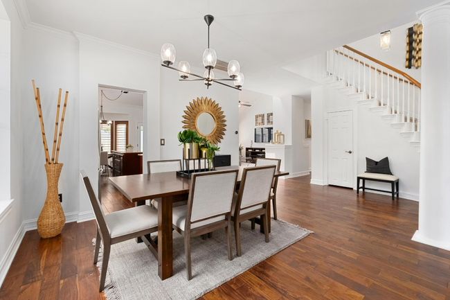 Dining room featuring stairway, wood finished floors, a chandelier, and ornamental molding | Image 6