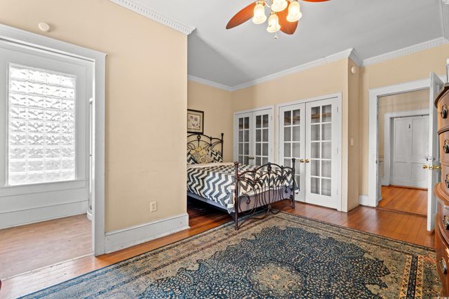 Bedroom with french doors, hardwood / wood-style floors, ornamental molding, and ceiling fan | Image 25