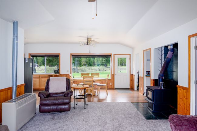 Living room with a wood stove, lofted ceiling, a ceiling fan, and a wainscoted wall | Image 86