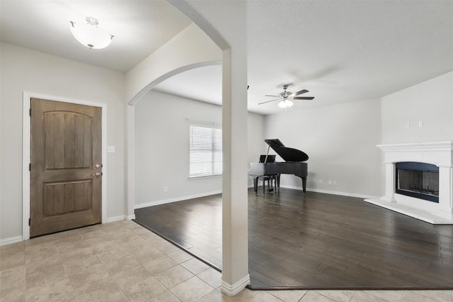 Foyer entrance with arched walkways, a ceiling fan, light wood-style flooring, a fireplace with raised hearth, and baseboards | Image 4
