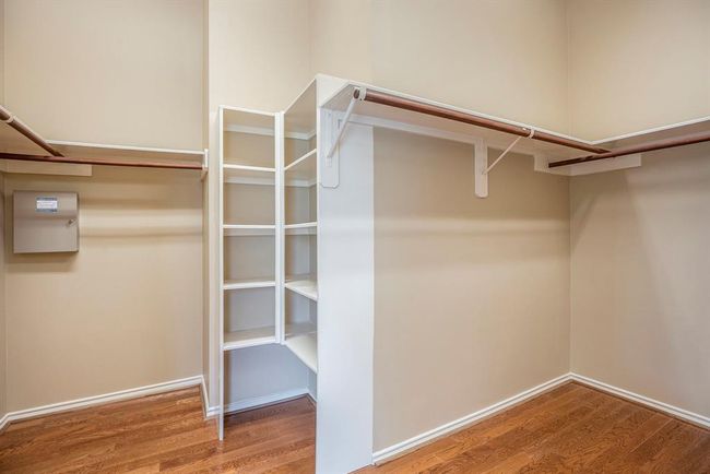 This oversized walk-in closet offers abundant storage with built-in shelving, dual hanging rods, and wood flooring throughout. Thoughtfully designed for organization, it provides ample space for everything from everyday essentials to seasonal pieces. | Image 22