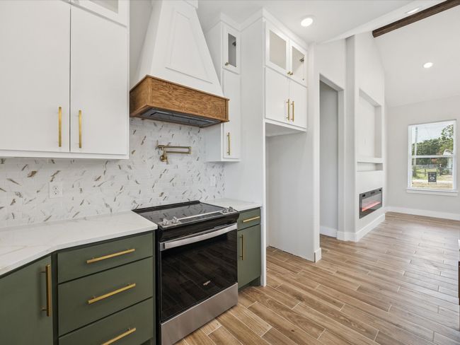 Kitchen with green cabinetry, premium range hood, stainless steel range with electric stovetop, white cabinetry, and recessed lighting | Image 14