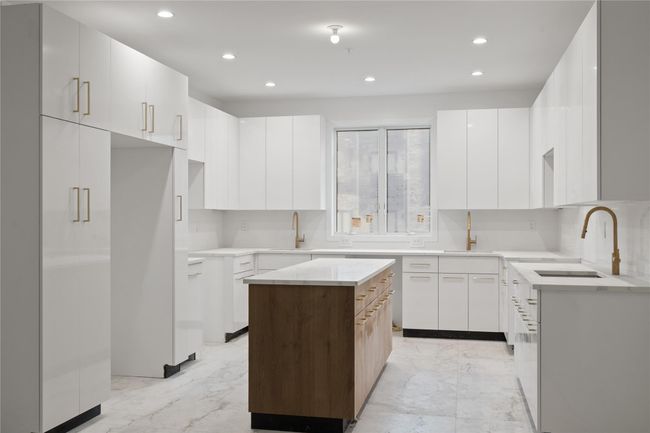 Kitchen with a sink, modern cabinets, a center island, recessed lighting, and light marble finish flooring | Image 9