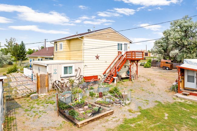Rear view of house with a vegetable garden, fence, and stairs | Image 12