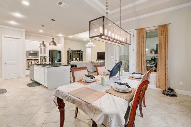 Dining room with ornamental molding, light tile patterned floors, recessed lighting, and a chandelier | Image 7