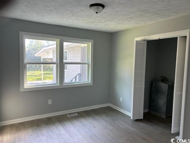 Unfurnished bedroom with a textured ceiling, multiple windows, wood finished floors, and baseboards | Image 25