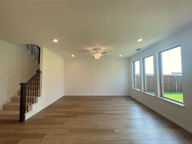 Empty room featuring a ceiling fan, wood finished floors, stairs, and recessed lighting | Image 8