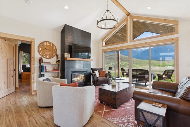 Living room with a chandelier, recessed lighting, light wood-style flooring, high vaulted ceiling, and a tile fireplace | Image 27
