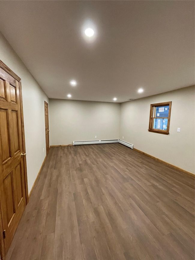 Room with recessed lighting, wood finished floors, a baseboard radiator, and baseboards | Image 6