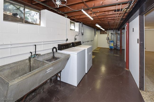 Clothes washing area with concrete block wall, gas water heater, laundry area, and washer and clothes dryer | Image 42
