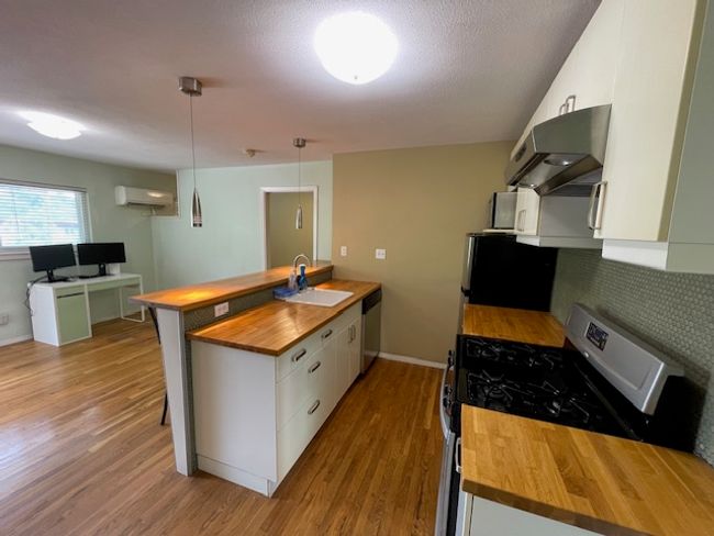 Kitchen featuring butcher block countertops, exhaust hood, gas range, and dishwasher | Image 6