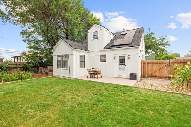 Rear view of house featuring board and batten siding, a shingled roof, a patio, solar panels, and a fenced backyard | Image 24