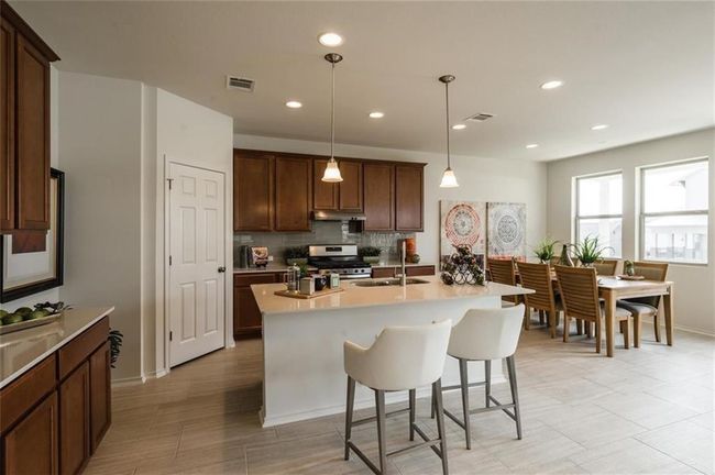 Kitchen with a kitchen bar, light countertops, stainless steel range oven, decorative backsplash, and under cabinet range hood | Image 14
