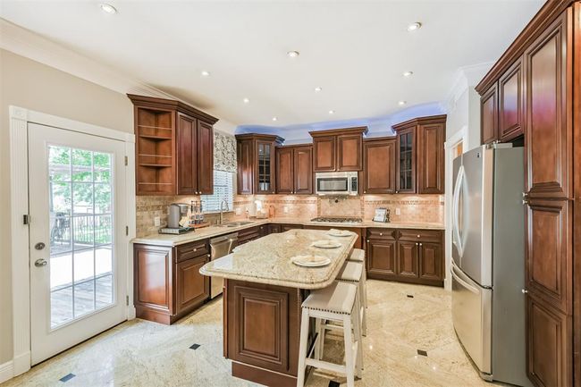 This kitchen boasts elegant granite countertops and a spacious island. | Image 11