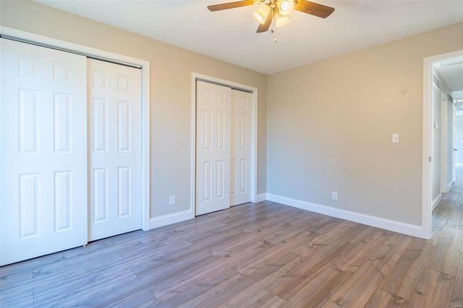 Unfurnished bedroom featuring ceiling fan, two closets, and light wood-style flooring | Image 19