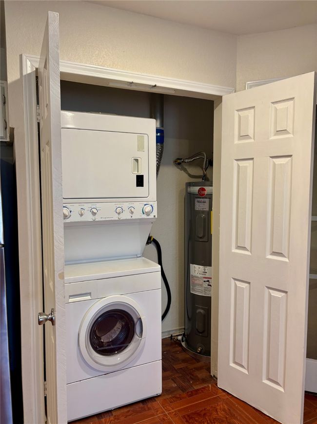 Laundry room featuring stacked washer and clothes dryer and recently installed water heater | Image 17