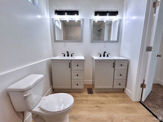 Bathroom featuring two vanities, wood finished floors, toilet, and a sink | Image 22
