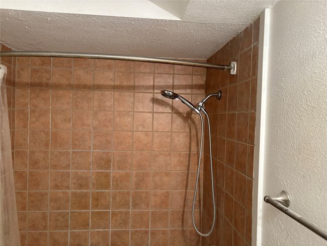 Bathroom view of a textured ceiling, a textured wall, and a tile shower | Image 13