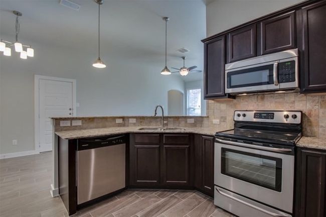 Kitchen with stainless steel appliances, a sink, decorative backsplash, and dark brown cabinets | Image 8