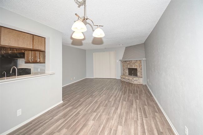 Unfurnished living room featuring light hardwood / wood-style floors, sink, a textured ceiling, and a fireplace | Image 15