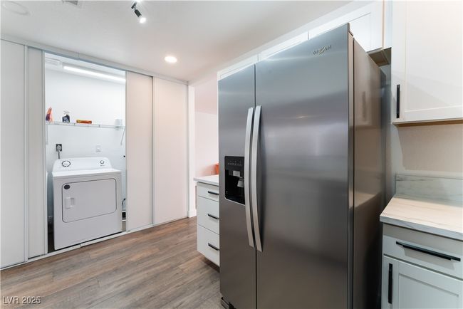 Kitchen featuring washer / clothes dryer, stainless steel fridge, light countertops, and light wood finished floors | Image 16