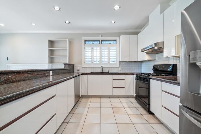 Kitchen featuring white cabinetry, stainless steel appliances, under cabinet range hood, and crown molding | Image 12