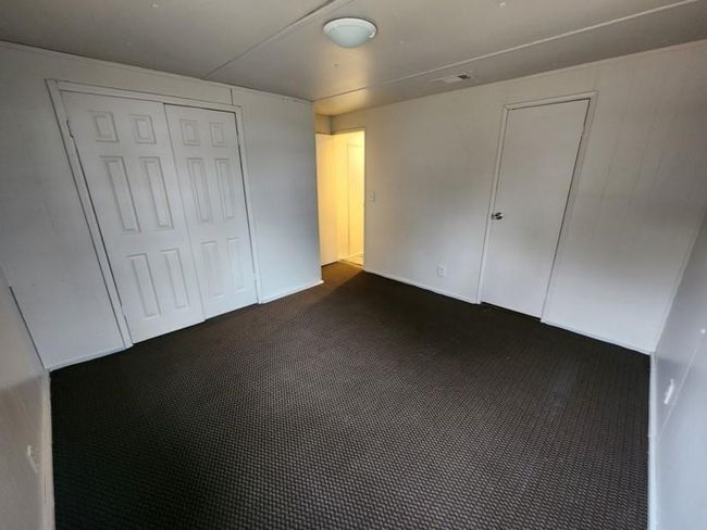 Unfurnished bedroom with dark colored carpet and a closet | Image 14