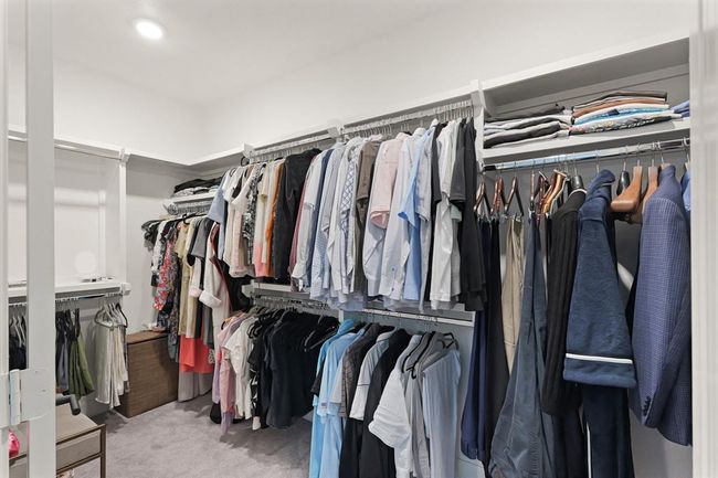 his spacious walk-in closet features ample hanging space, shelving for folded clothes, and a neutral carpeted floor, offering organized and convenient storage. | Image 18