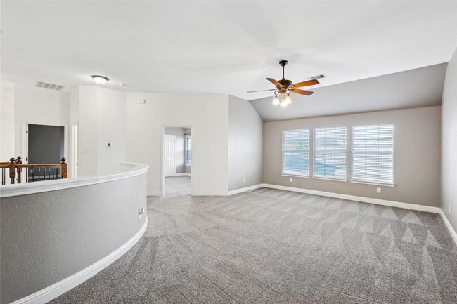 Unfurnished room with light colored carpet, vaulted ceiling, and ceiling fan | Image 29