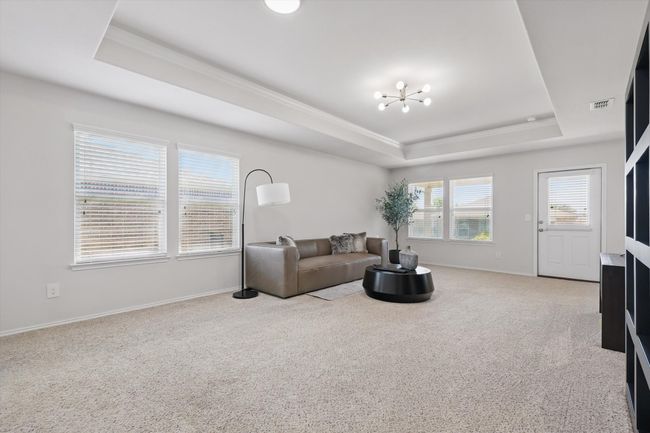 Living room with a raised ceiling, carpet, ornamental molding, and an inviting chandelier | Image 9