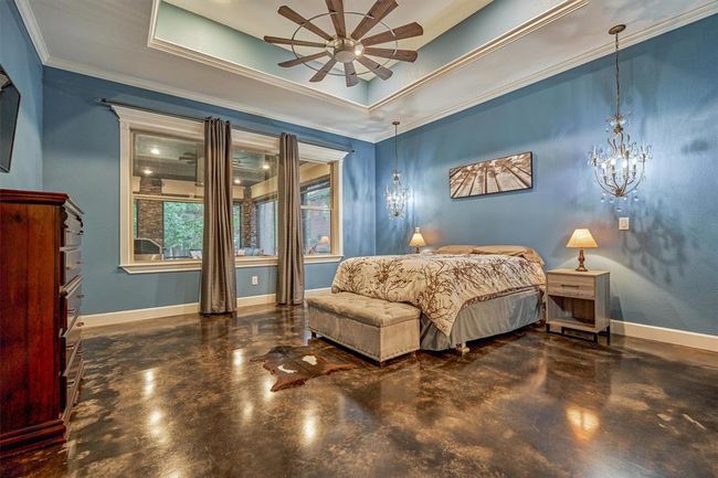 The primary bedroom features a custom ceiling design and elegant crystal chandeliers on either side of the bed, providing sophisticated accent lighting. | Image 27