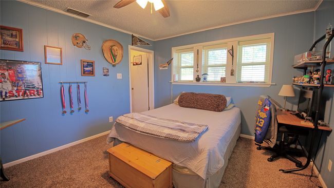 Bedroom featuring visible vents, a ceiling fan, ornamental molding, a textured ceiling, and carpet flooring | Image 8