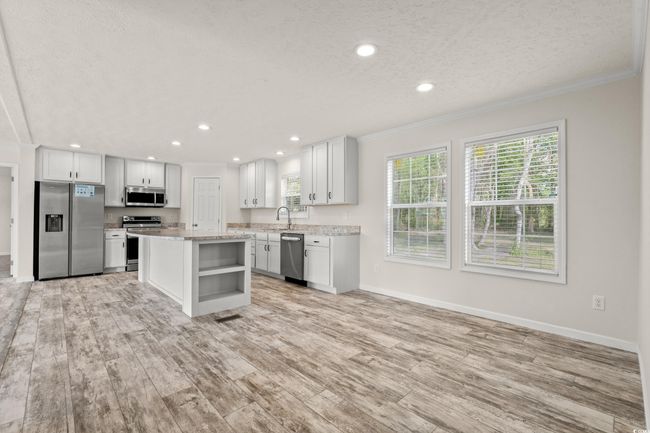 Kitchen featuring appliances with stainless steel finishes, ornamental molding, and plenty of natural light | Image 7