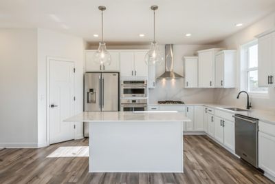 Photo is of the actual home. The stunning gourmet kitchen features a large center island, quartz countertops, LVP floors, stainless appliances and more! | Image 2