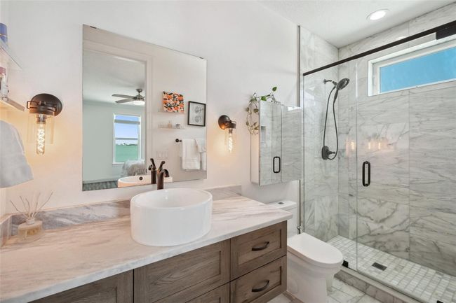 The secondary master suite's bathroom features real marble floors, shower walls and countertops, as well as a solid wood custom floating vanity. | Image 64