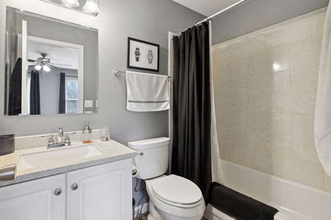 En suite for Bedroom 2 with tiled tub surround and granite countertop. | Image 29