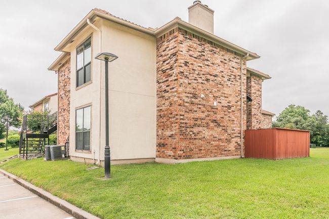 View of home's exterior featuring stairway, a chimney, central AC unit, and a lawn | Image 33