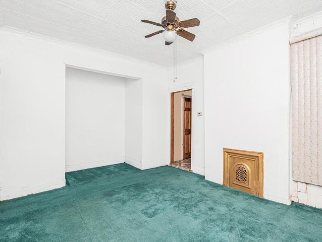 Empty room with an ornate ceiling, ceiling fan, ornamental molding, and carpet floors | Image 5